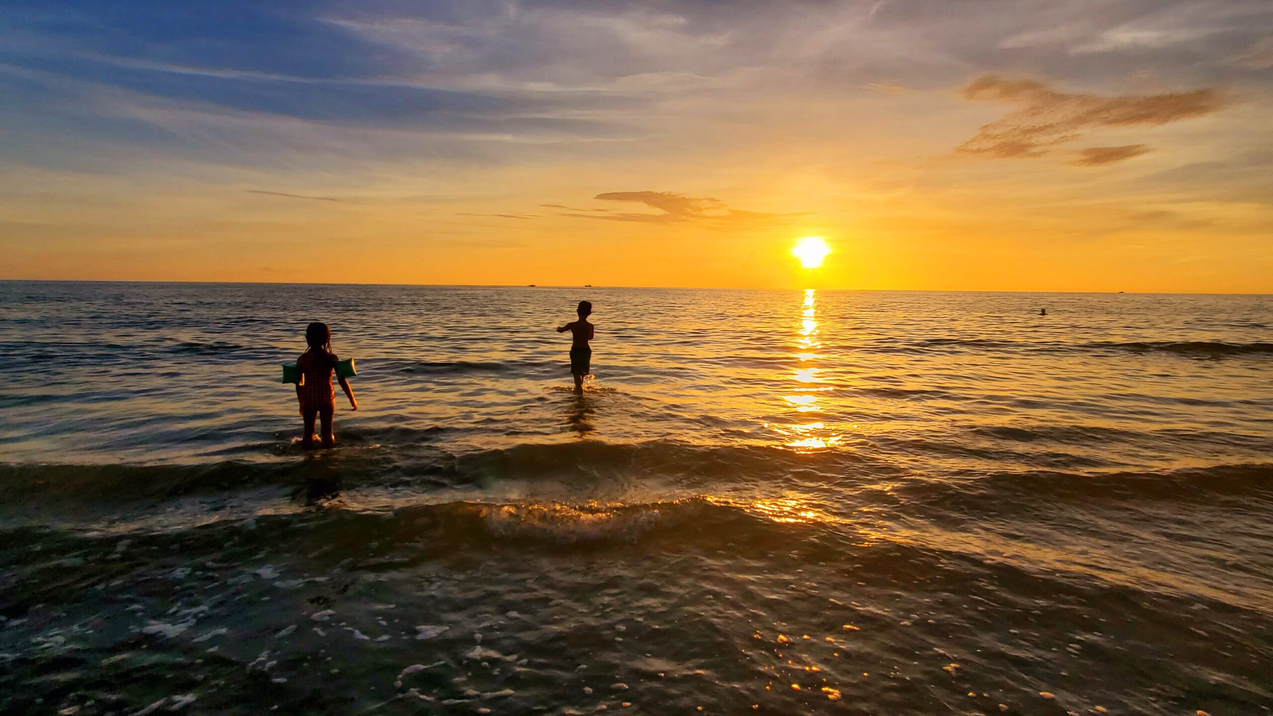Family enjoying a sunset swim on a Southwest Florida beach